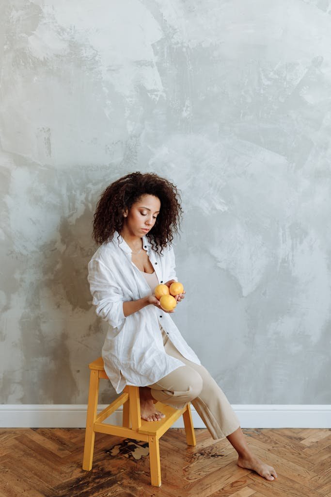 A Woman in White Long Sleeves Sitting on a Wooden Stool